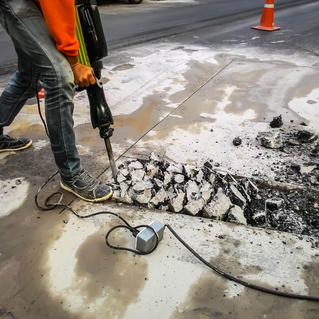 pessoa quebrando concreto com equipamento maven